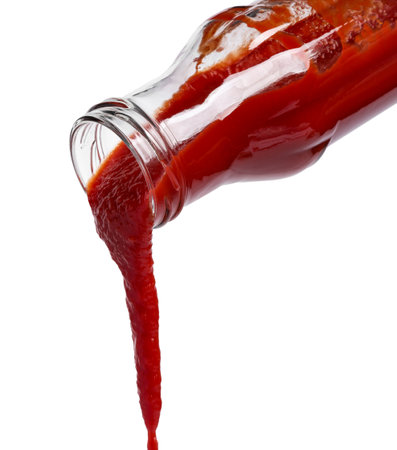 Pouring tasty red ketchup from glass bottle isolated on whiteの写真素材