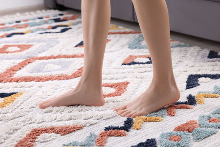 Woman walking on carpet with pattern at home, closeupの写真素材