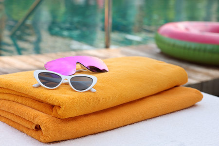 Beach towels and sunglasses on sun lounger near outdoor swimming pool. Luxury resortの写真素材