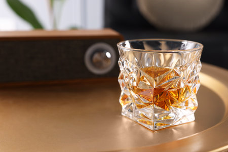 Alcohol drink on golden table in room, space for text. Relax at home