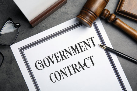 Government contract, wooden gavel, pen and eyeglasses on gray table, flat lay
