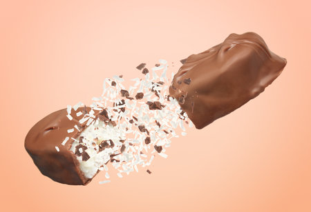 Broken chocolate bar with shredded coconut in air on pale coral backgroundの写真素材