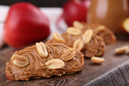Pieces of fresh apple with peanut butter on wooden board, closeupの写真素材