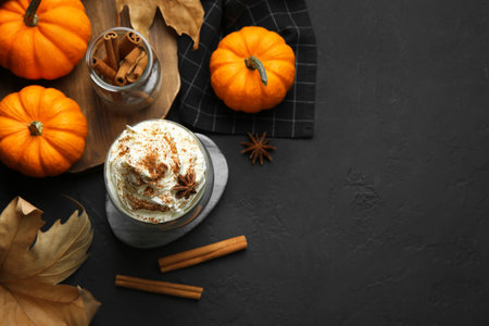 Flat lay composition with glass of pumpkin spice latte on black table. Space for textの写真素材