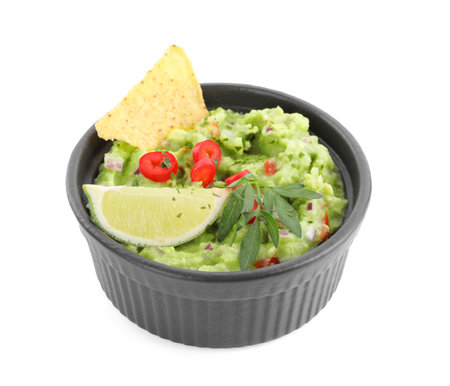 Delicious guacamole served with nachos chips, lime and pepper isolated on whiteの写真素材
