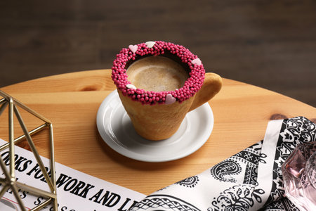 Delicious edible biscuit cup of coffee decorated with sprinkles on wooden tableの写真素材