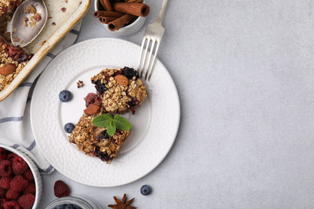 Tasty baked oatmeal with berries and almonds on light gray table, flat lay. Space for textの写真素材