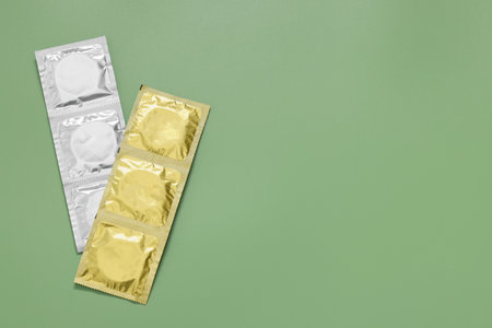 Packaged condoms on light green background, top view with space for text. Safe sexの写真素材
