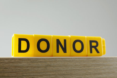 Word Donor made of yellow cubes on wooden table, closeupの写真素材