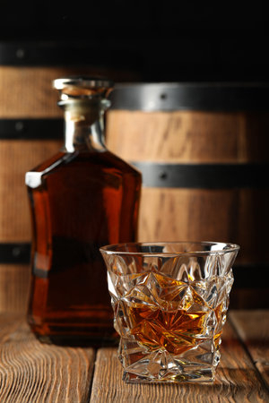 Glass and bottle of tasty whiskey on wooden tableの写真素材
