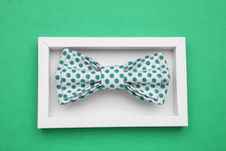 Stylish bow tie with polka dot pattern in box on green background, top viewの写真素材