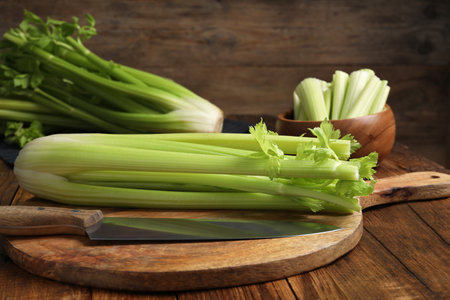 Fresh green celery bunches and knife on wooden tableの写真素材