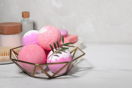 Beautiful aromatic bath bombs and green twig on white marble table, space for textの写真素材