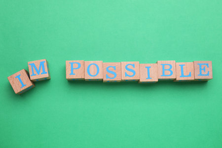 Motivation concept. Changing word from Impossible into Possible by removing wooden cubes with...