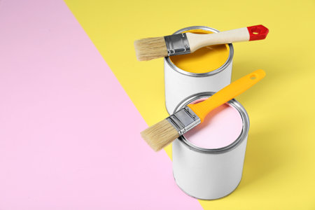Cans of colorful paints with brushes on color background. Space for textの写真素材