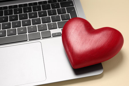 Long-distance relationship concept. Laptop and decorative heart on beige background, closeupの写真素材