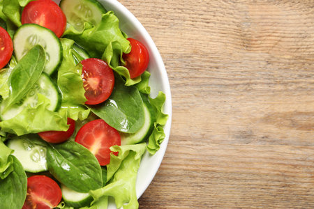 Delicious vegetable salad on wooden table, top view. Space for textの写真素材
