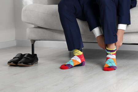 Man putting on colorful socks at home, closeupの写真素材