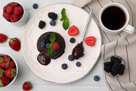 Plate with delicious chocolate fondant, berries and mint on white tiled table, flat layの写真素材