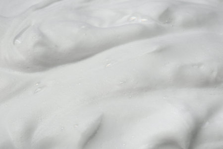 Foam as background, closeup. Face cleanser, skin care cosmetic
