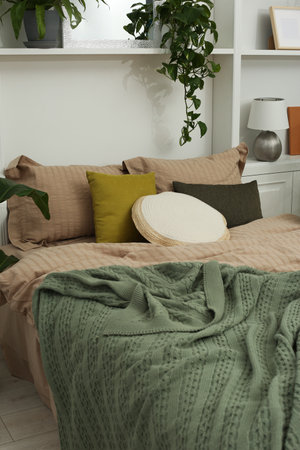 Comfortable bed and different houseplants in bedroom. Interior design