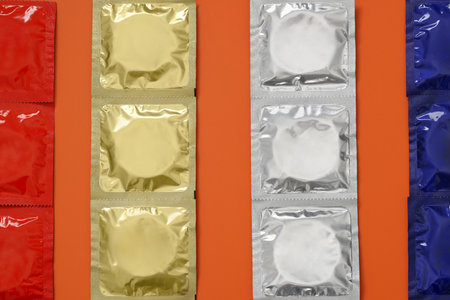 Packaged condoms on orange background, flat lay. Safe sexの写真素材