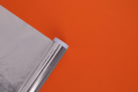 Roll of aluminum foil on orange background, top view. Space for textの写真素材