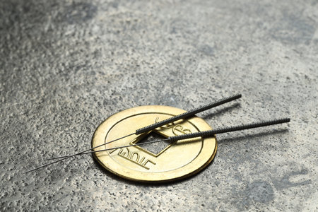 Acupuncture needles and ancient coin on gray textured table, closeup. Space for textの写真素材