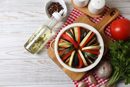 Cooking delicious ratatouille. Dish with different fresh cut vegetables on white wooden table, flat lay. Space for textの写真素材