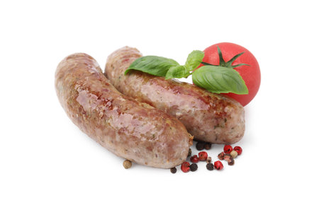 Tasty homemade sausages, peppercorns, tomato and basil leaves isolated on whiteの写真素材
