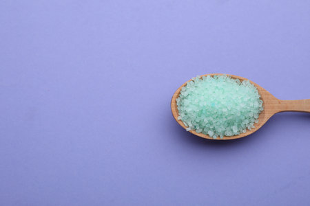 Spoon with turquoise sea salt on violet background, top view. Space for textの写真素材