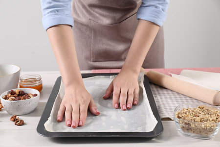 Woman making delicious baklava at white wooden table, closeupの写真素材