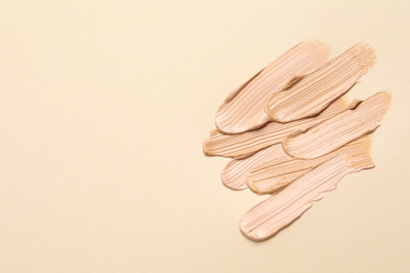 Samples of skin foundation on beige background, flat lay. Space for textの写真素材