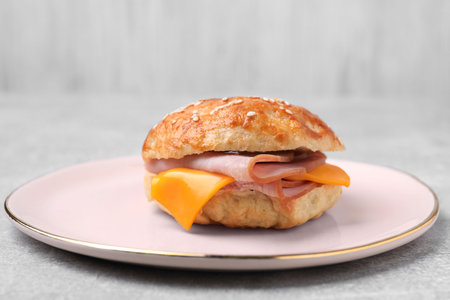 Delicious bagel with ham and cheese on light gray tableの写真素材