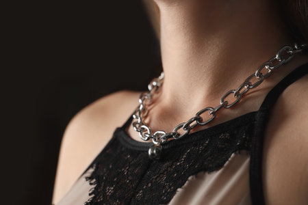 Woman wearing stylish metal chain with pendant on black background, closeup. Luxury jewelryの写真素材