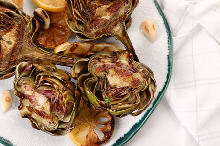 Plate with tasty grilled artichokes on white table, top viewの写真素材