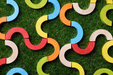 Colorful wooden pieces of play set on green grass, flat lay. Educational toy for motor skills...