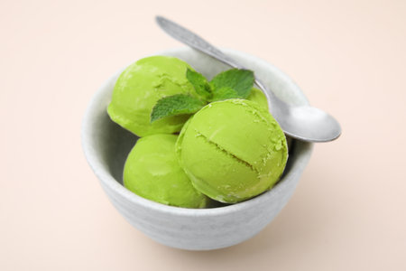 Tasty matcha ice cream and spoon in bowl on beige table, closeupの写真素材