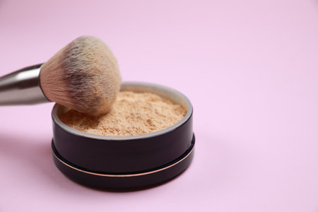 Face powder and brush on pink background, closeup. Space for textの写真素材