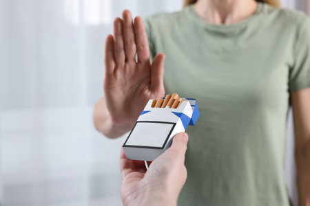 Woman refusing cigarettes on light background, closeup. Quitting smoking conceptの写真素材