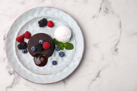 Delicious chocolate fondant served with fresh berries and ice cream on white marble table, top view. Space for textの写真素材