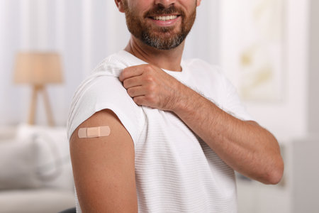 Man with sticking plaster on arm after vaccination at home, closeupの写真素材