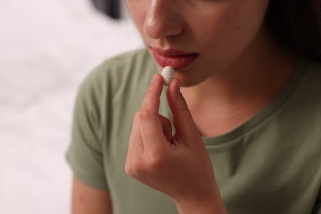 Woman taking antidepressant pill on blurred background, closeupの写真素材
