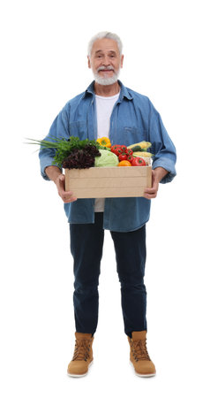 Harvesting season. Happy farmer holding wooden crate with vegetables on white backgroundの写真素材