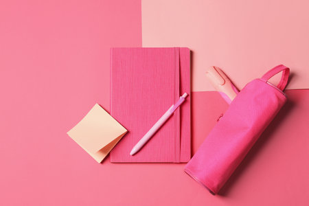 Bright notebook and case with other stationery on pink background, flat layの写真素材