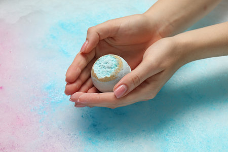 Woman holding bath bomb over water with foam, closeupの写真素材