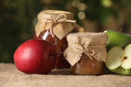 Delicious apple jam and fresh fruits on burlap against blurred background, closeupの写真素材
