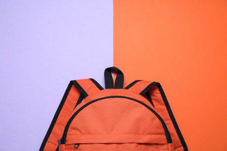 Stylish orange backpack on color background, top view. Space for text