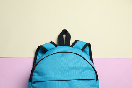 Stylish light blue backpack on color background, top view