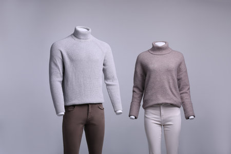 Male and female mannequins dressed in stylish outfits on gray backgroundの写真素材